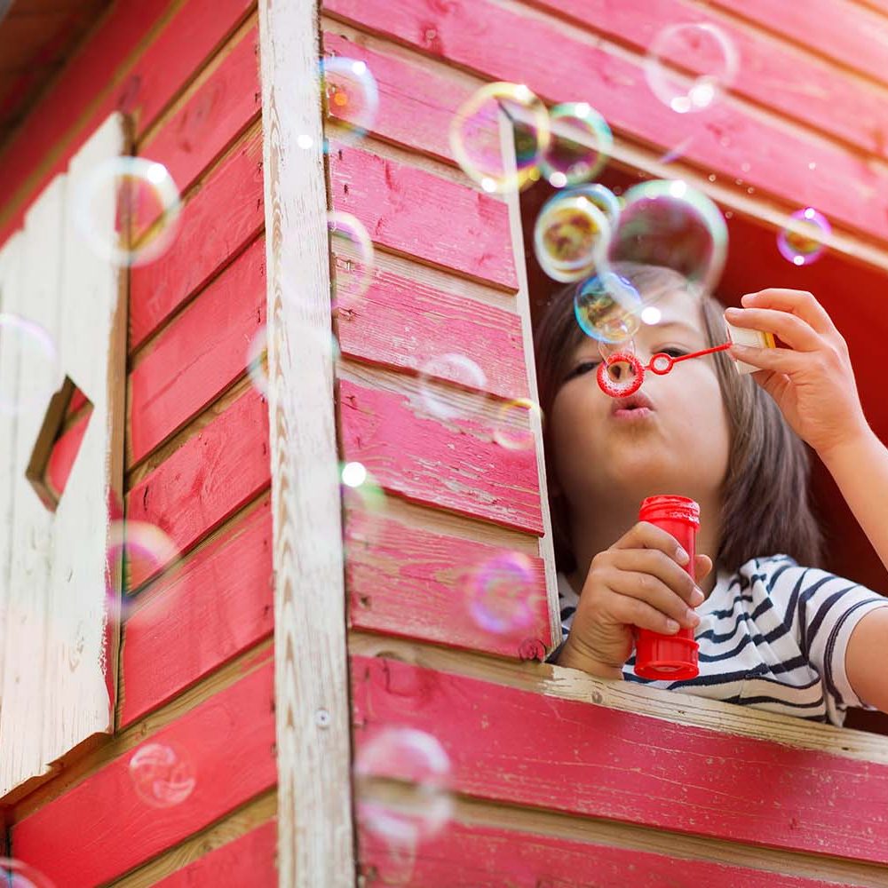 Boy blowing bubbles in a wooden playhouse